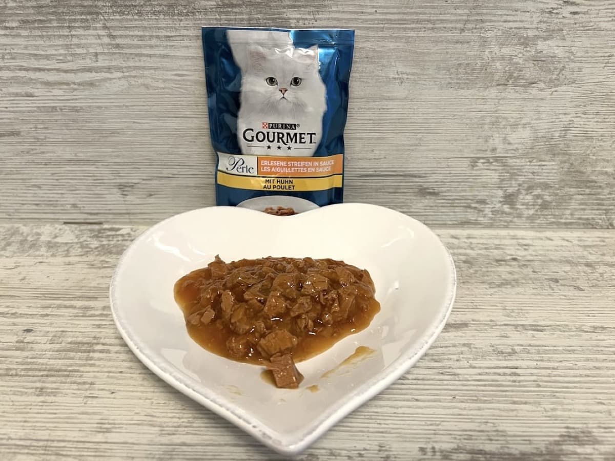 Gourmet Perle Katzenfutter Pouch mit Streifen in Soße auf einem Teller