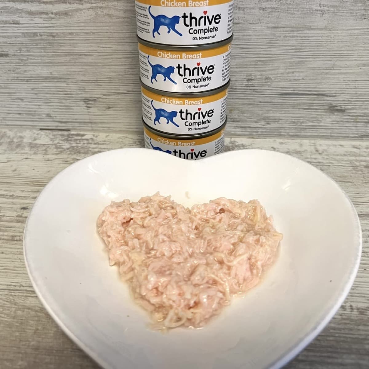 Thrive Complete Katzenfutter Dosen mit Hühnerfleisch auf einem herzförmigen Teller
